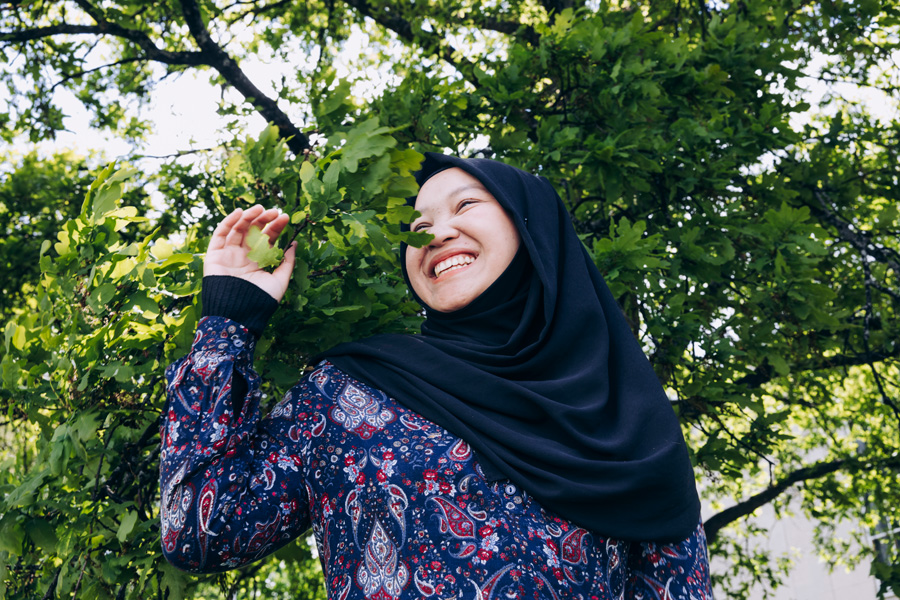 Student with scarf smiling among trees