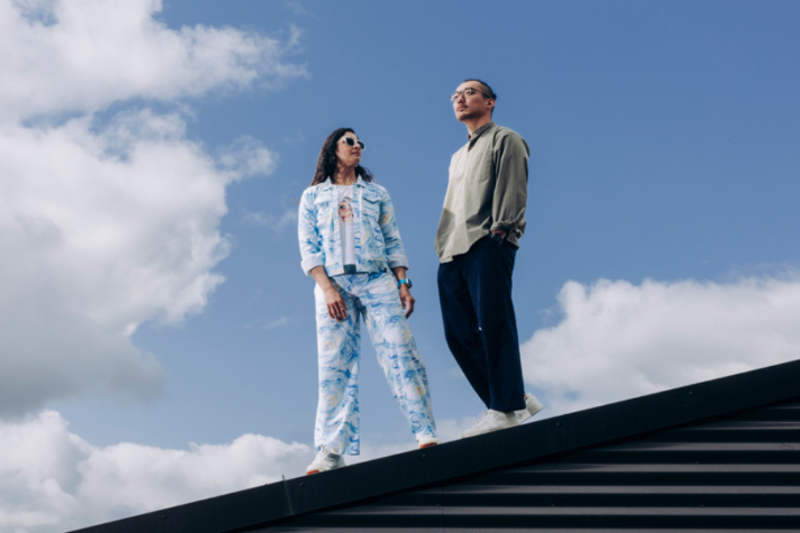 Two students standing on a rooftop with sky background